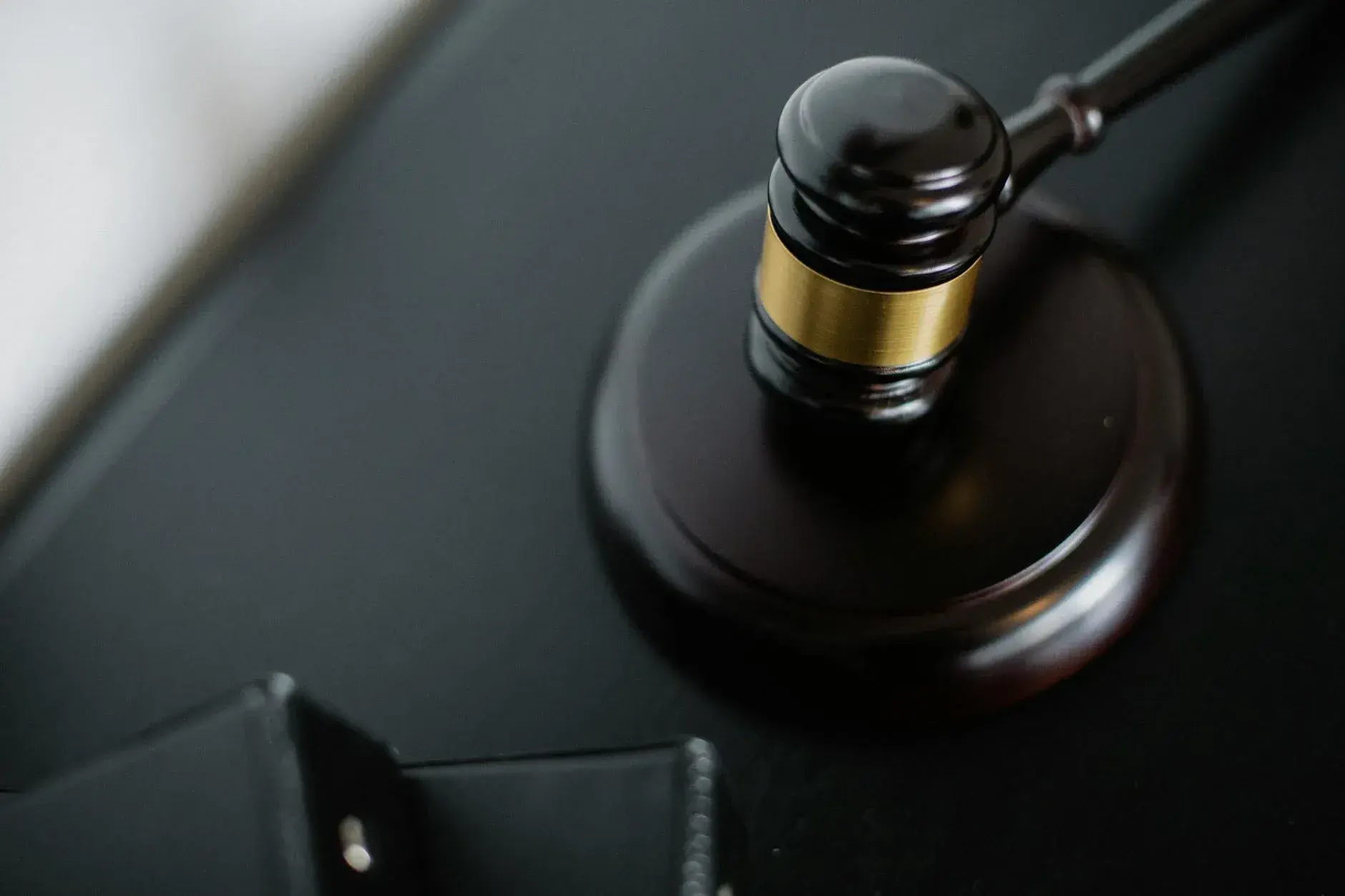 A close-up of a wooden judge's gavel on a black desk, representing the principles of justice and law.