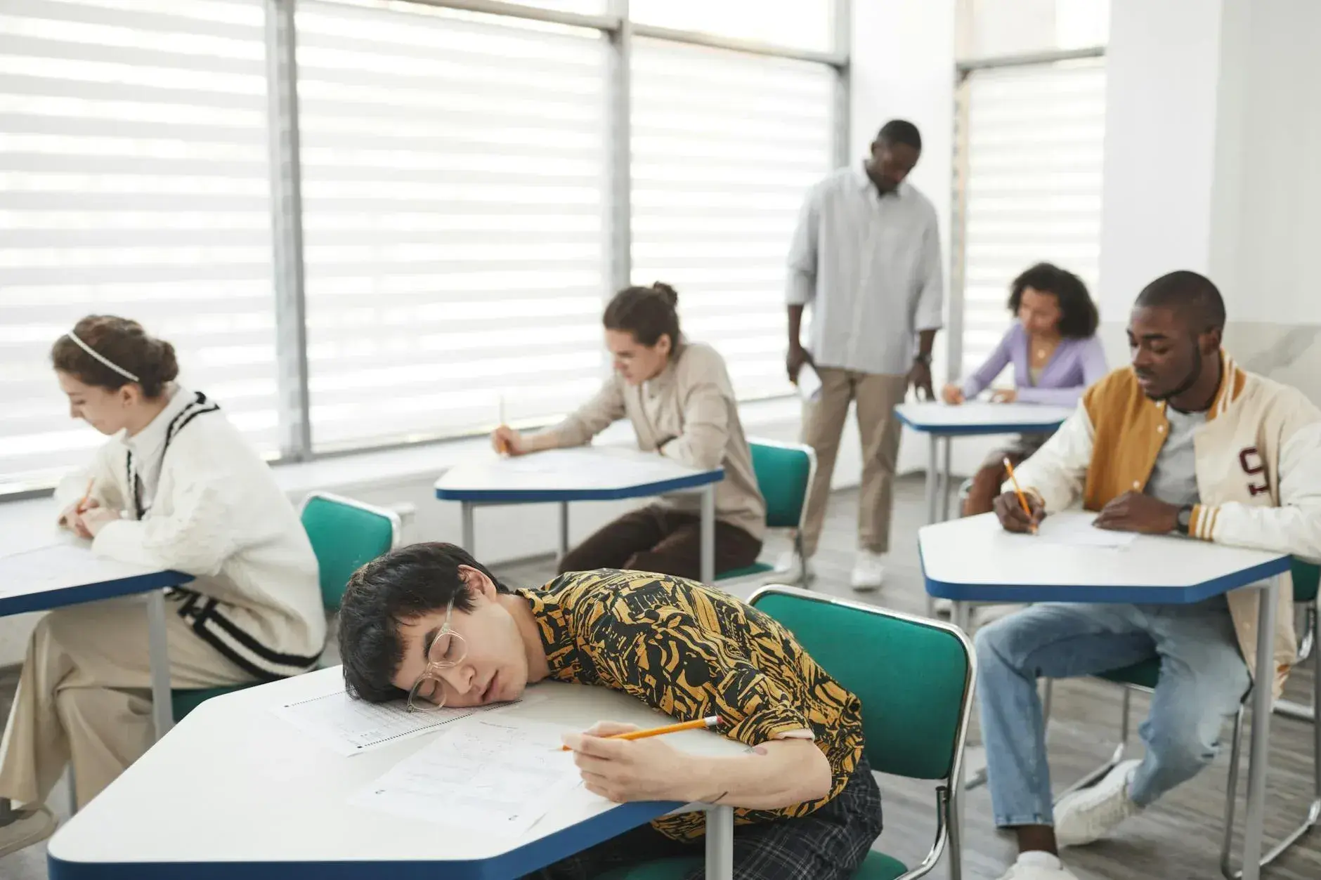 Diverse group of students focused on exams in a classroom setting.