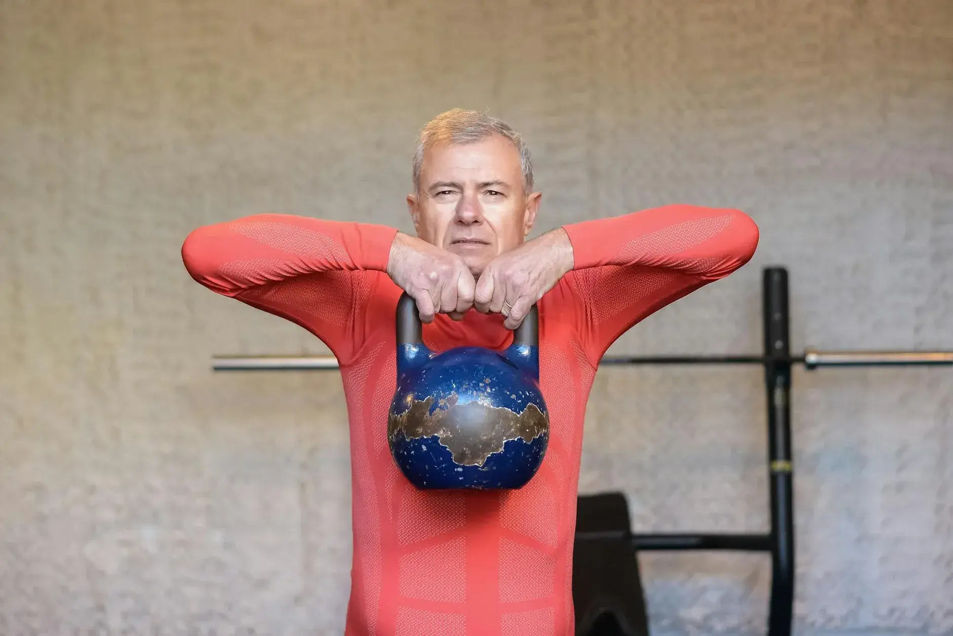 En ældre mand udfører styrketræning med en kettlebell. Billedet formidler sundhed, styrke og aktiv aldring.