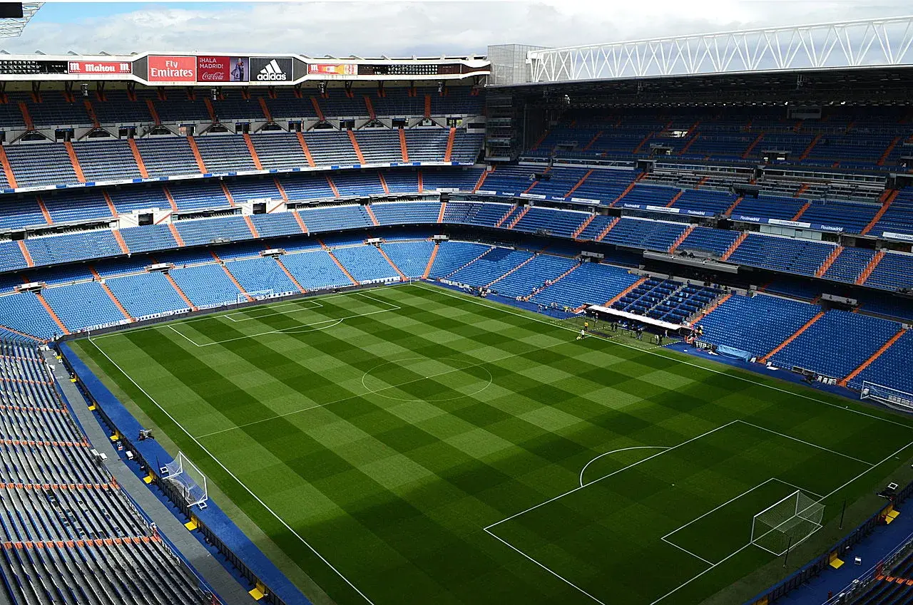 Et bredt panoramabillede af Santiago Bernabéu Stadion i Madrid. Perspektivet viser stadionets samlede form og den markante placering i byens sportslandskab.