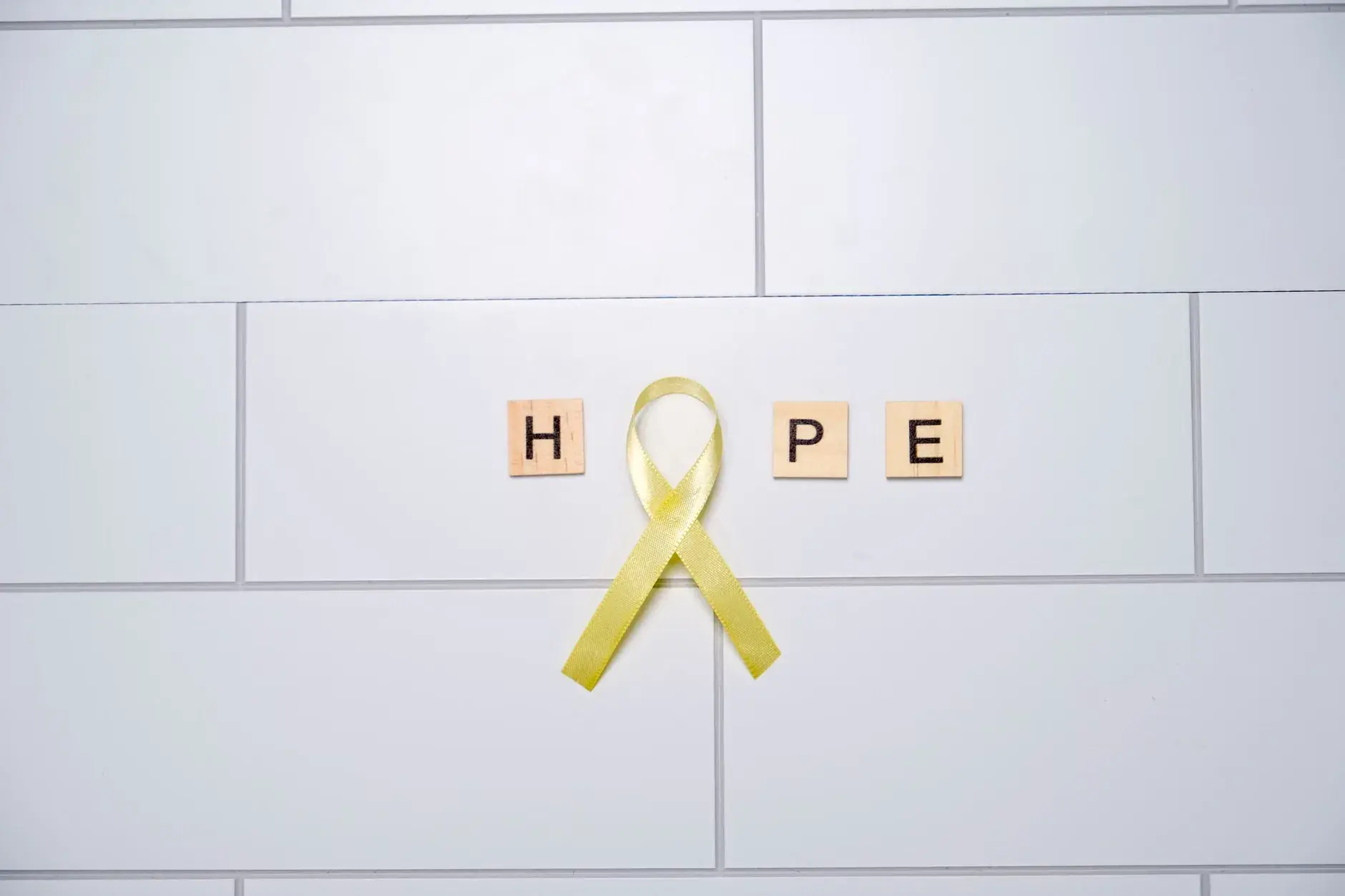 Et billede af håb symboliseret gennem gule bånd, der danner ordet 'hope' på en hvid baggrund.