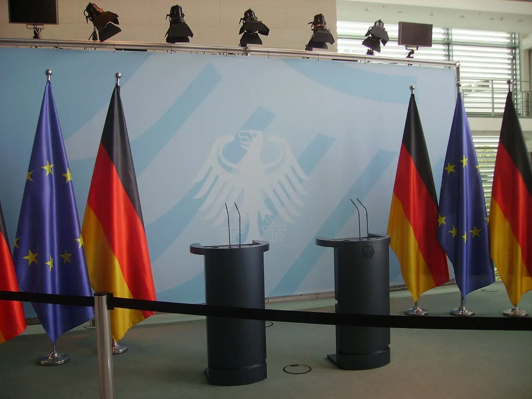 Et luftfoto af tomme talerstole med EU og tyske flag foran Forbundskansleriet i Berlin. Billedet viser en symbolsk scene for europæisk samarbejde.