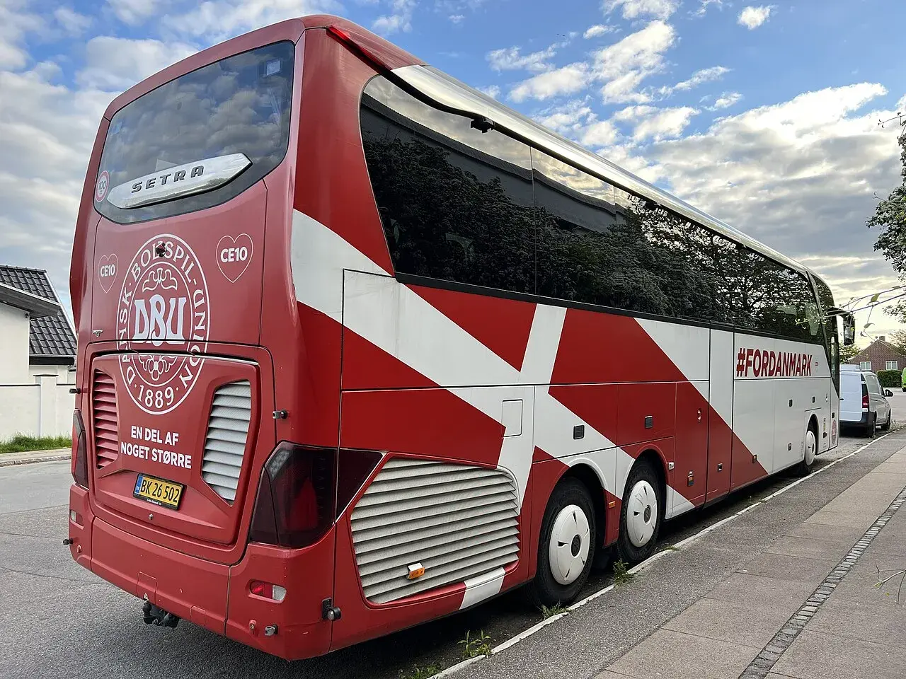 A white Setra bus with the Danish Football Association logo and flag, parked near residential areas in Copenhagen.