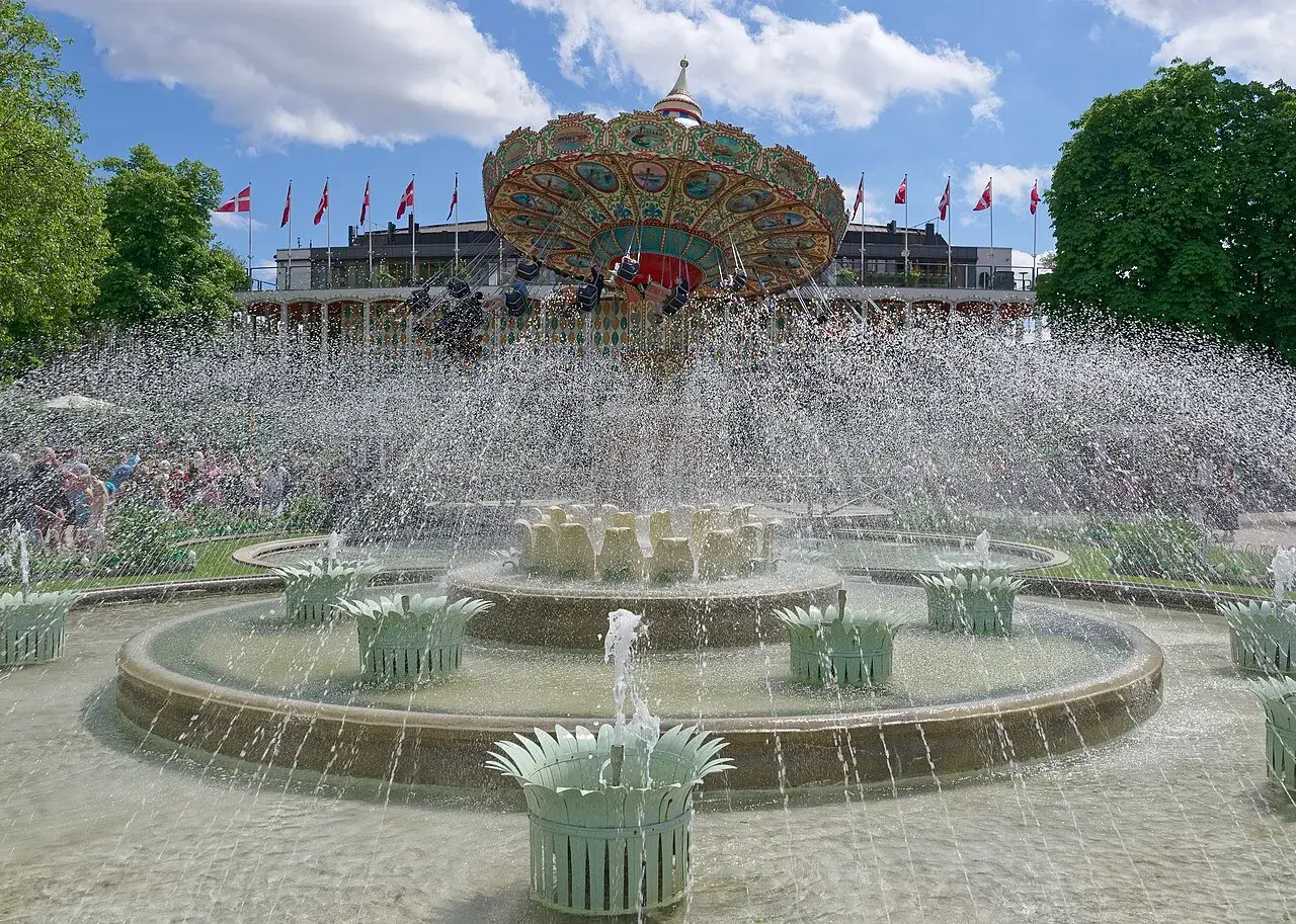 A stunning fountain in the Tivoli Gardens, Copenhagen, reflecting the surrounding park landscape.