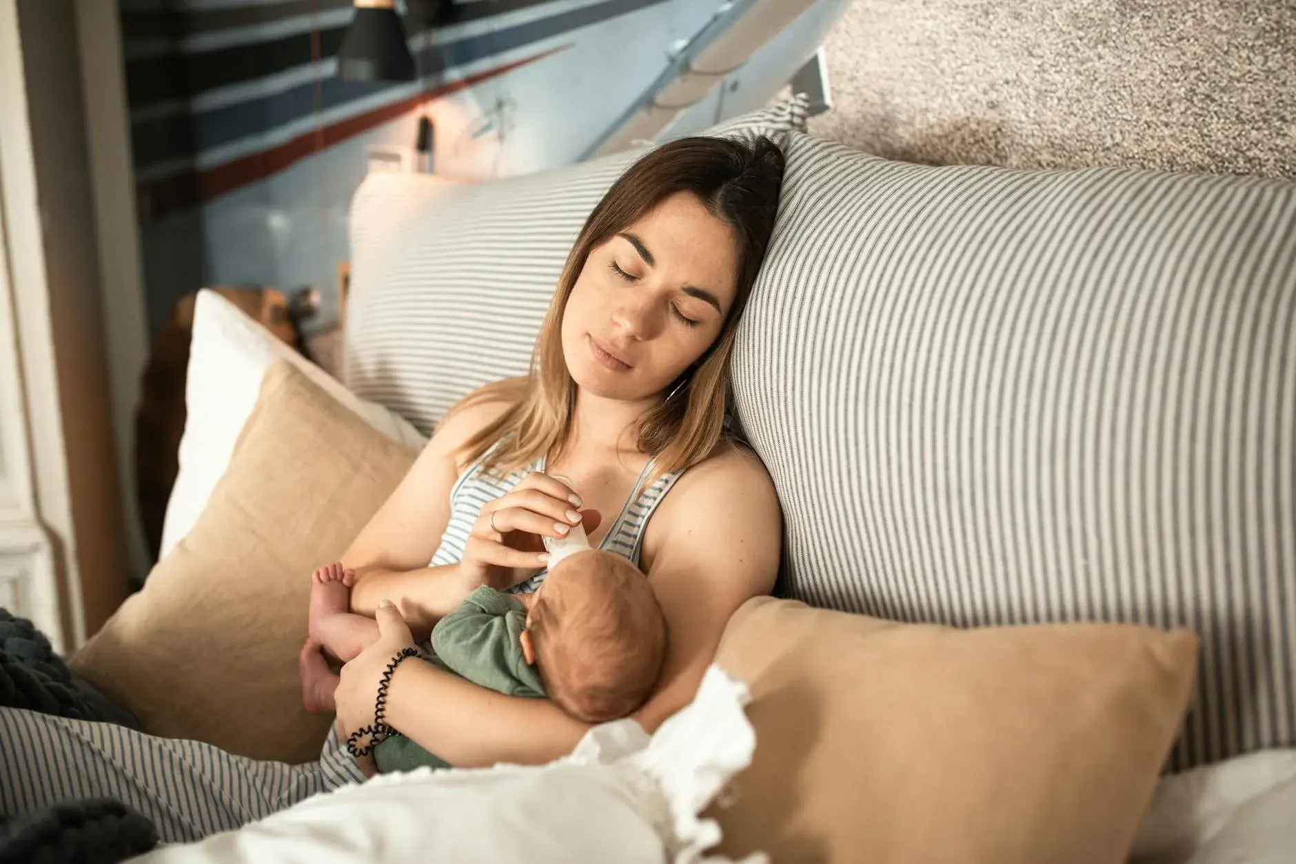 En mor nyder et fredfyldt øjeblik med sin nyfødte baby i hjemlige omgivelser.