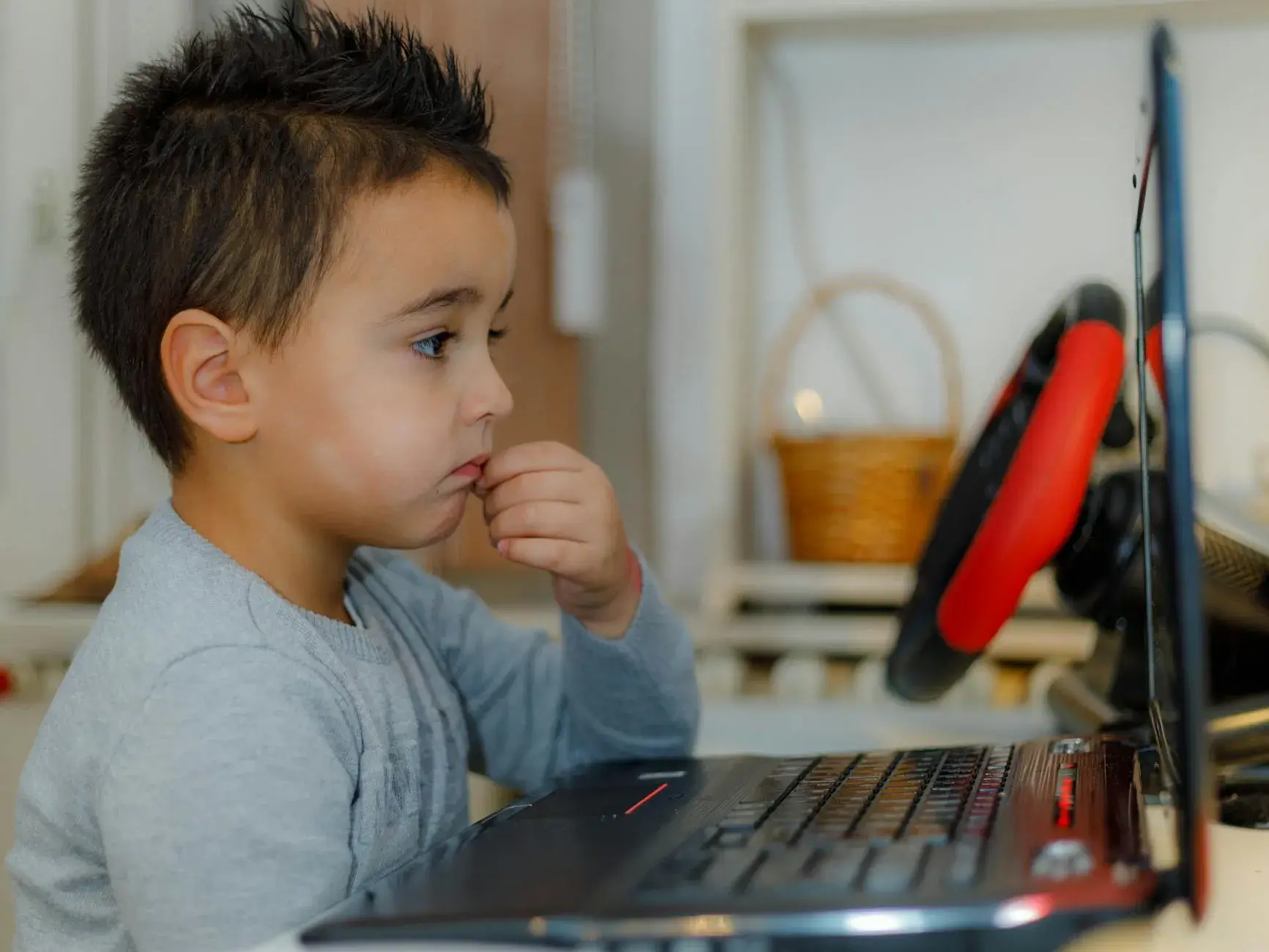 A young child focused on a laptop for educational purposes in a home setting.