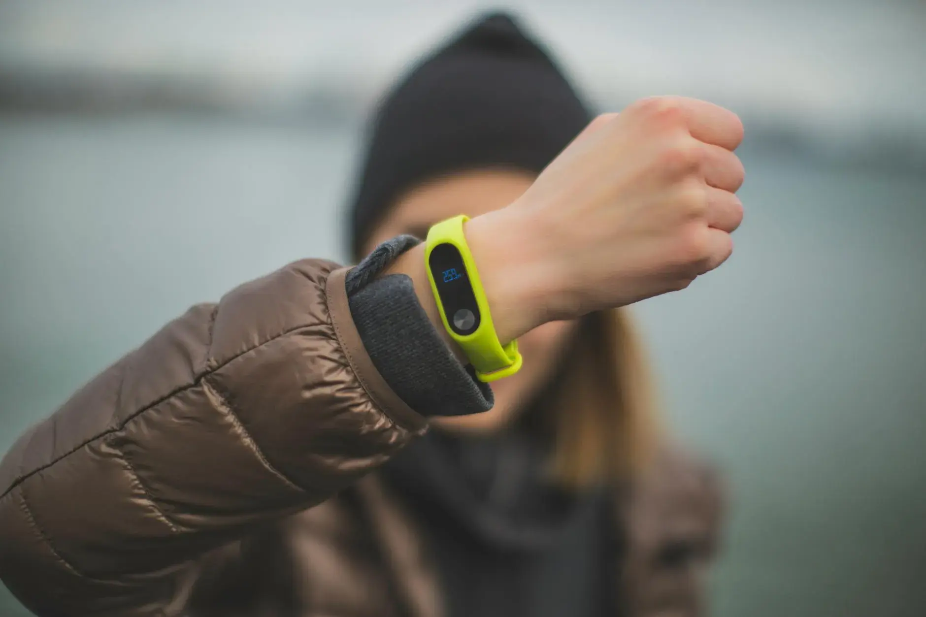 Et close-up af en person, der holder en fitness-tracker frem, så teknologien og den aktive hverdag tydeligt fremgår. Billedet signalerer sundhed, tracking og moderne vaner.