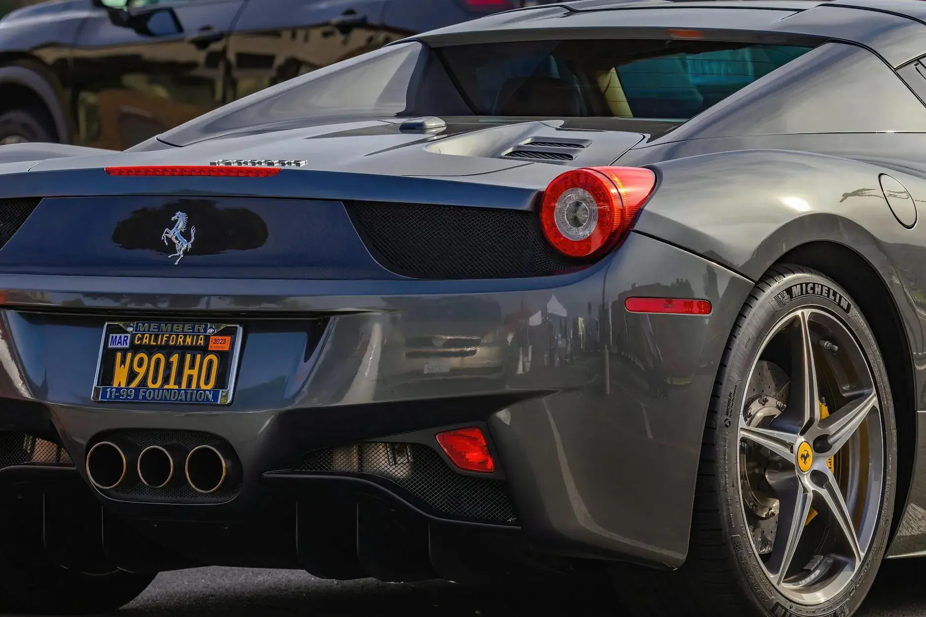 Et tæt nærbillede af en elegant grå Ferrari, der fremhæver bilens luksuriøse design og ikoniske emblem. Fokus er på bilens detaljer og overflader.
