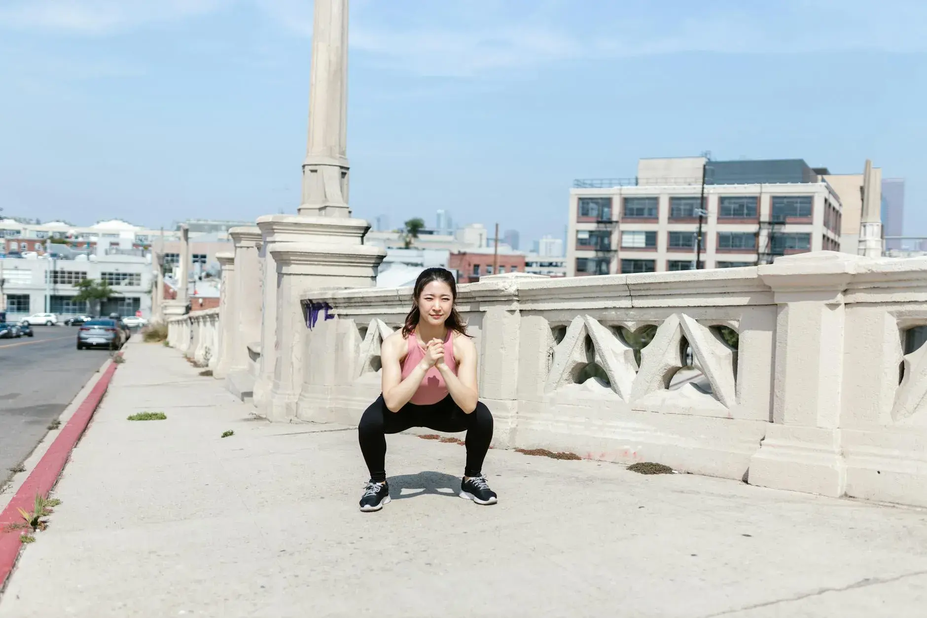 A dynamic woman performs squats on a city sidewalk, embodying urban fitness and determination.