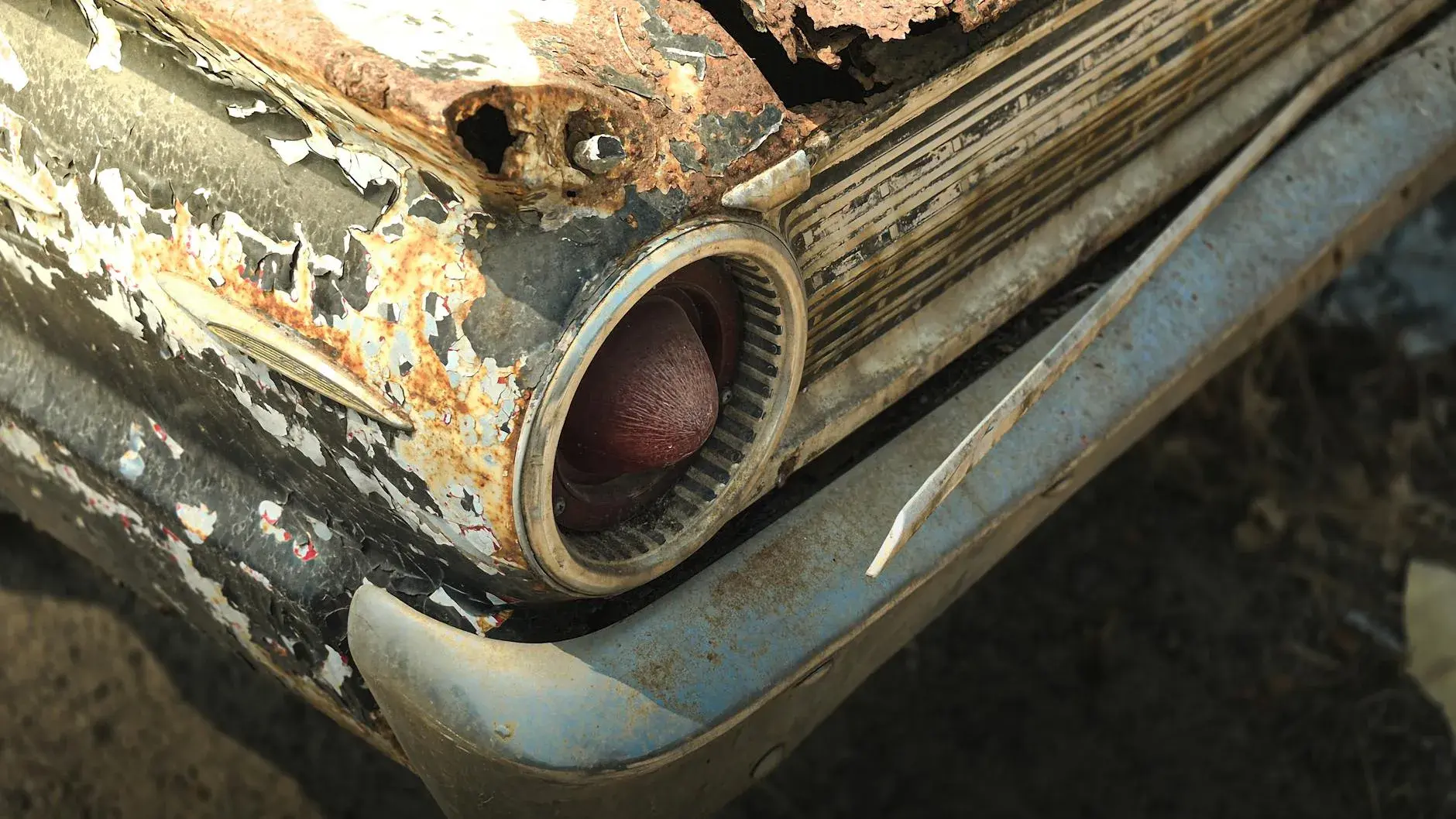 A detailed shot of a deteriorating vintage car showing signs of age with visible rust and peeling paint.