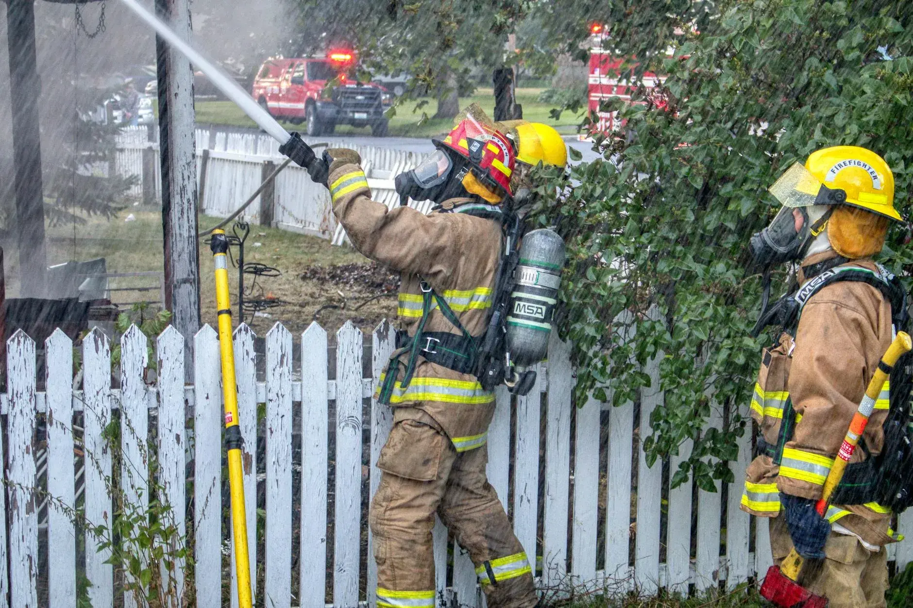 Brandmænd i beskyttelsesudstyr arbejder sammen om at slukke en brand. Scenen illustrerer indsats, samarbejde og handlekraft under en akut situation.