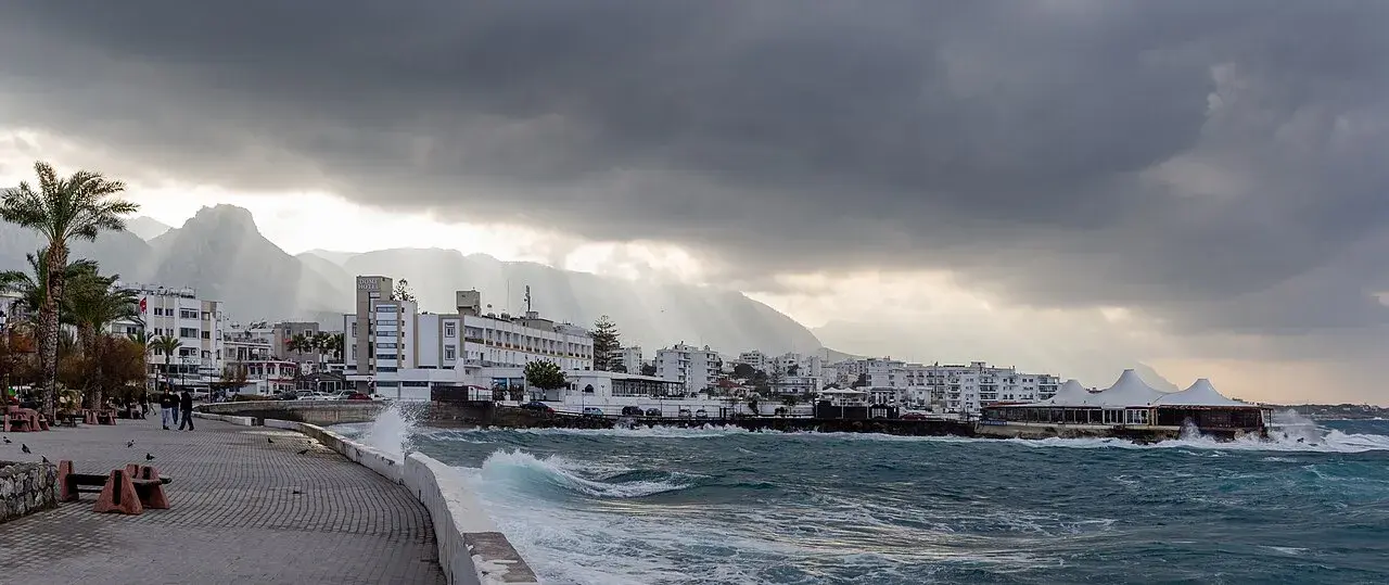 Et roligt kystlandskab i Kyrenia med det karakteristiske Dome Hotel i baggrunden. Havet og kystlinjen skaber en naturskøn ramme omkring hotellet.