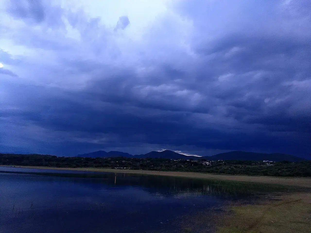 Fotografi af lagunen El Rodeo ved solnedgang i Miacatlán. Stemningen er præget af det varme aftenlys over vandet.