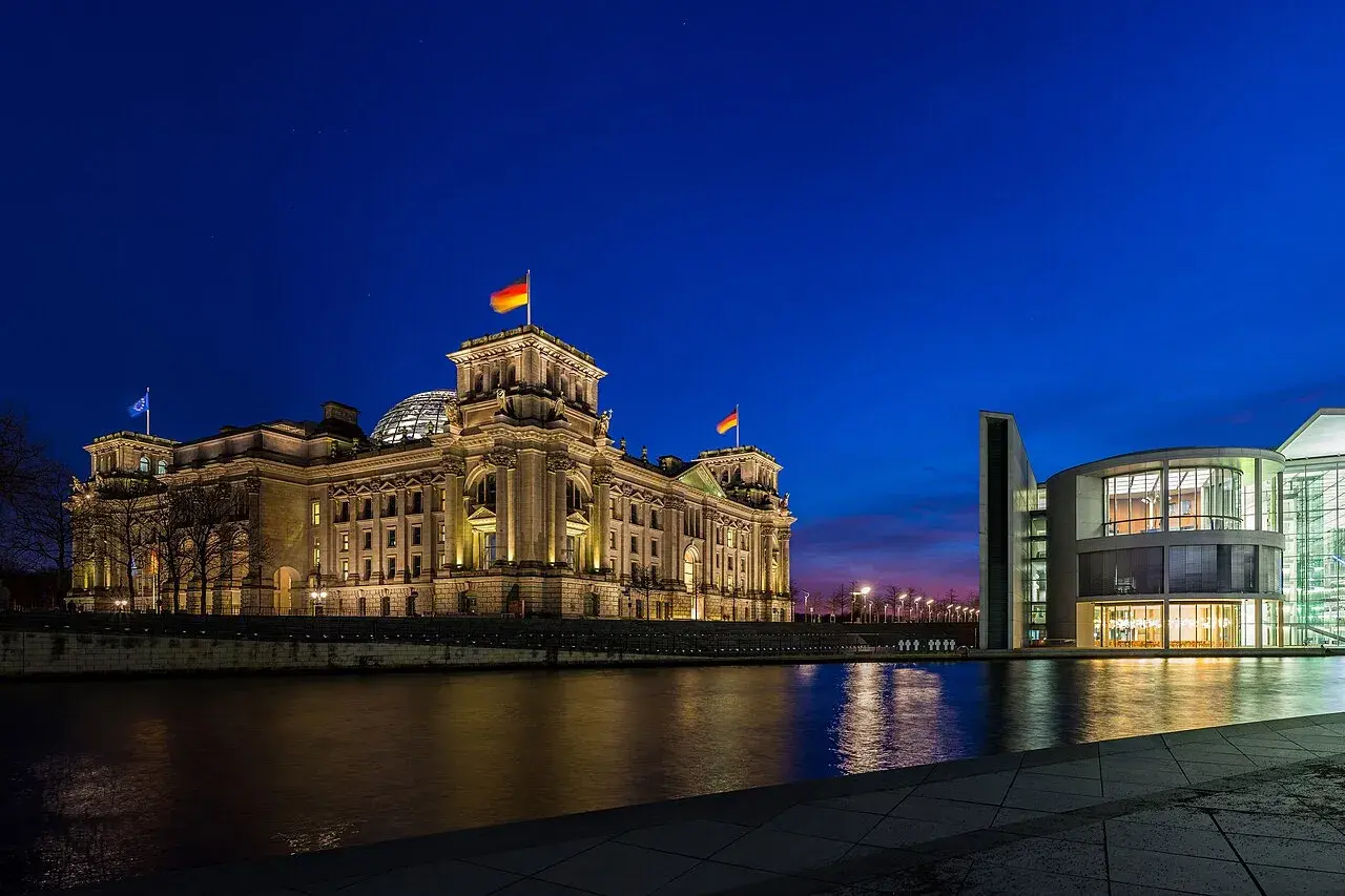 Reichstag-bygningen ses til venstre, mens Paul-Löbe-Haus’ østside ligger til højre langs floden Spree. Billedet er taget i blå time.