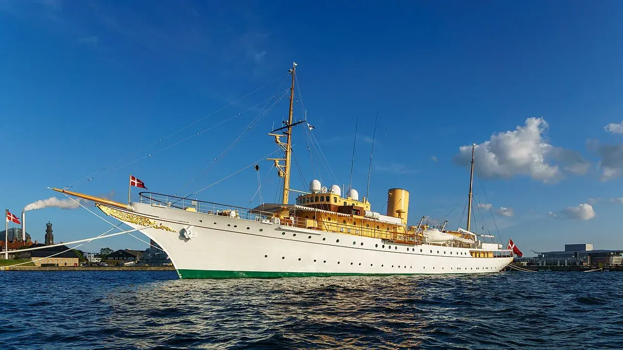 HDMY Dannebrog ses i København. Billedet er velegnet til artikler om dansk kongehus, skibe og maritime ceremonier.