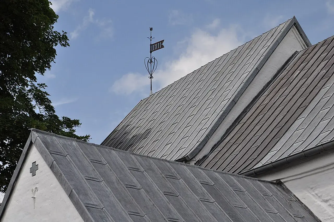 Detaljebillede fra Jelling Kirke. Fokus er på kirkens arkitektoniske elementer og overflader.