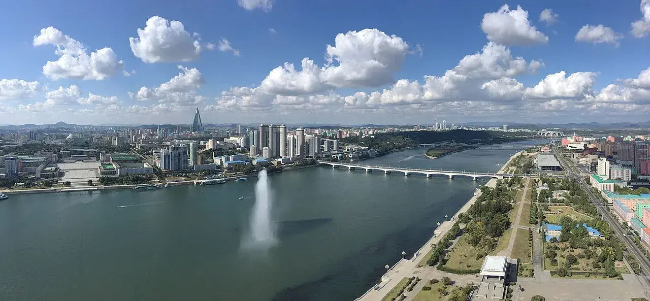 En panoramaudsigt over Pyongyang set fra Juche-tårnet. Billedet viser byens skyline og landskabet omkring.