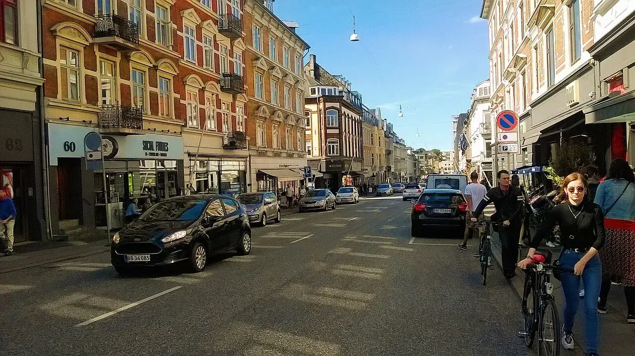 En politibetjent håndcuff’er en mistænkt under en anholdelse i et bymiljø. Billedet formidler en situation med kontrol og sikkerhed i det offentlige rum.
