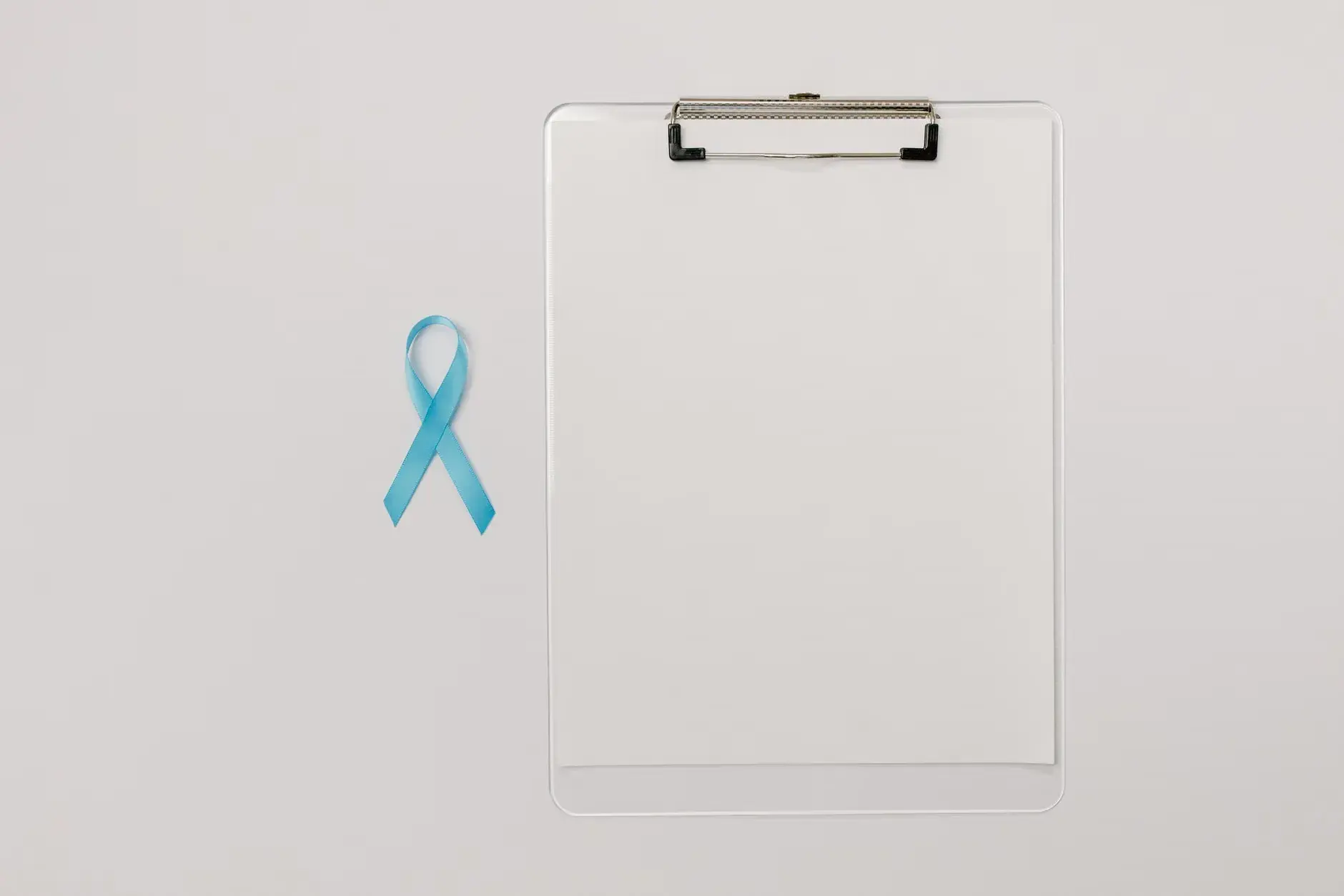 Et fladt motiv med et blått prostatakræft-opmærksomhedsbånd og en clipboard, der symboliserer sundhedstjek. Billedet formidler fokus på forebyggelse og tidlig indsats.