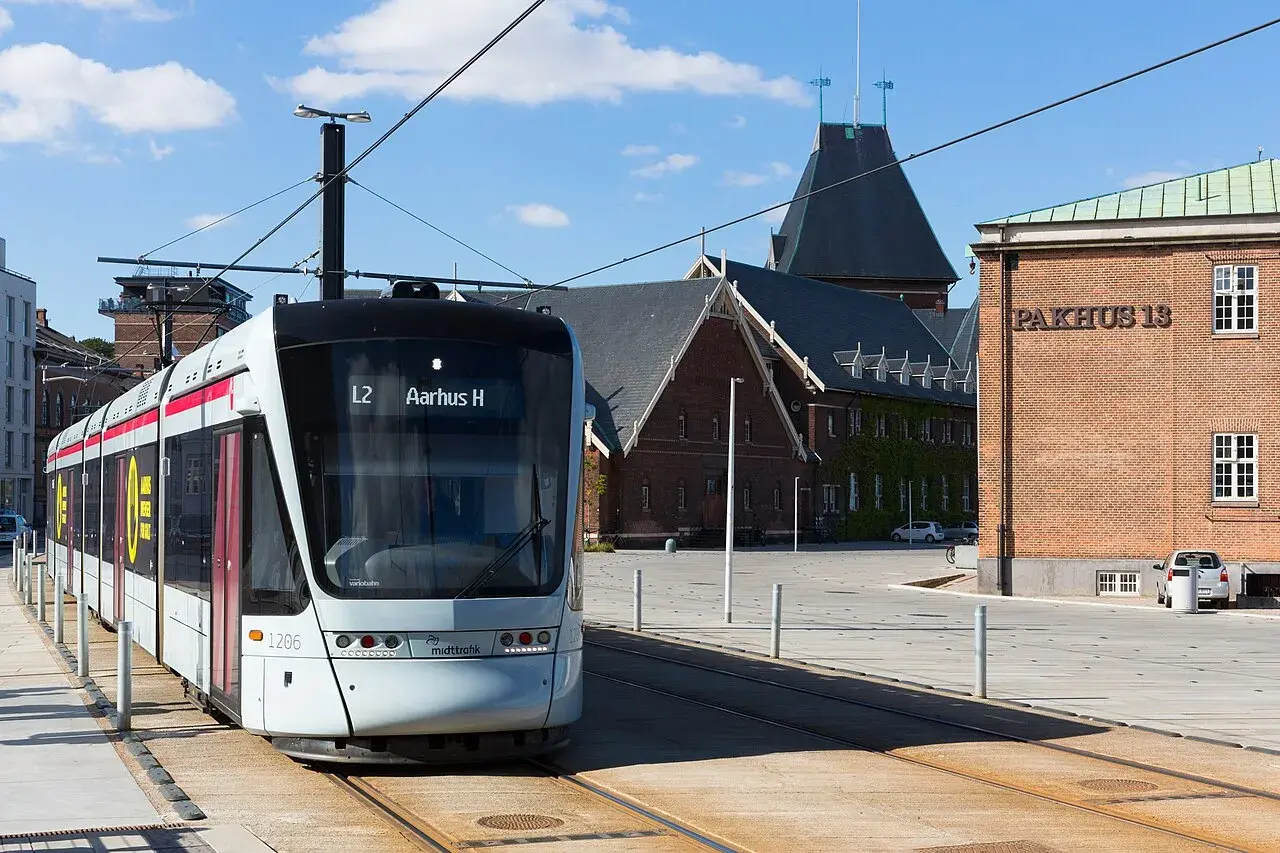 En sporvogn (Stadler Variobahn) kører i Havnegade i Aarhus. Billedet fanger byens trafik og byrum i et klassisk gadeperspektiv.