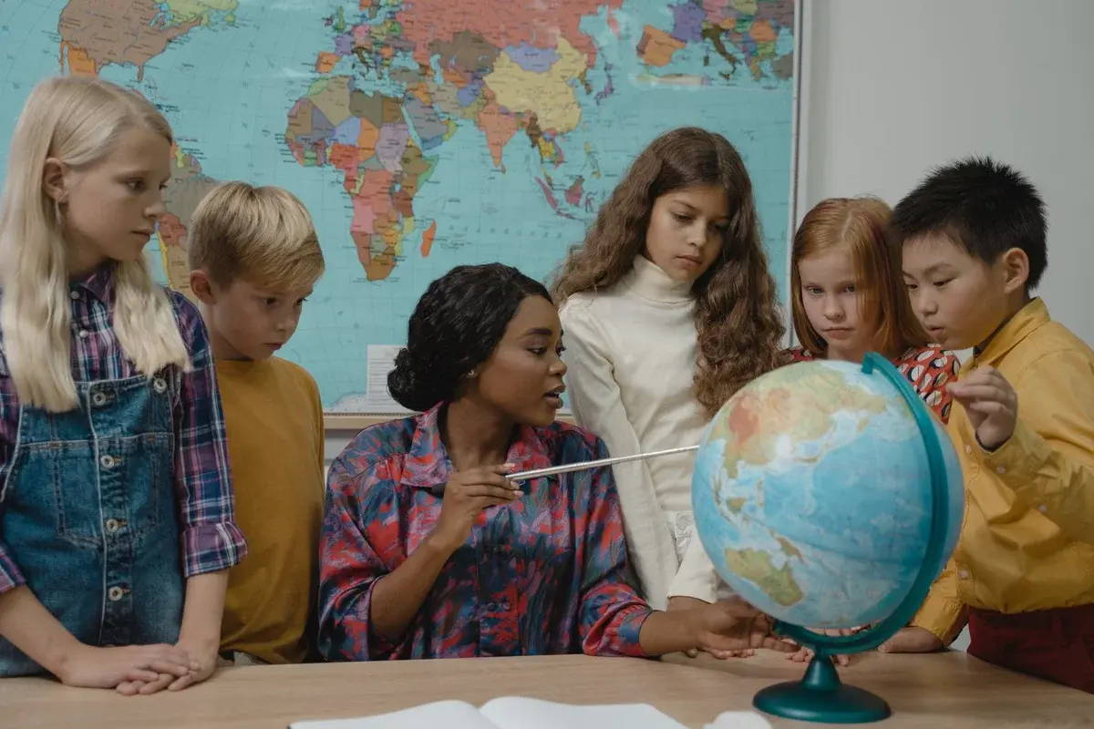 Teacher and diverse children learning geography using a globe