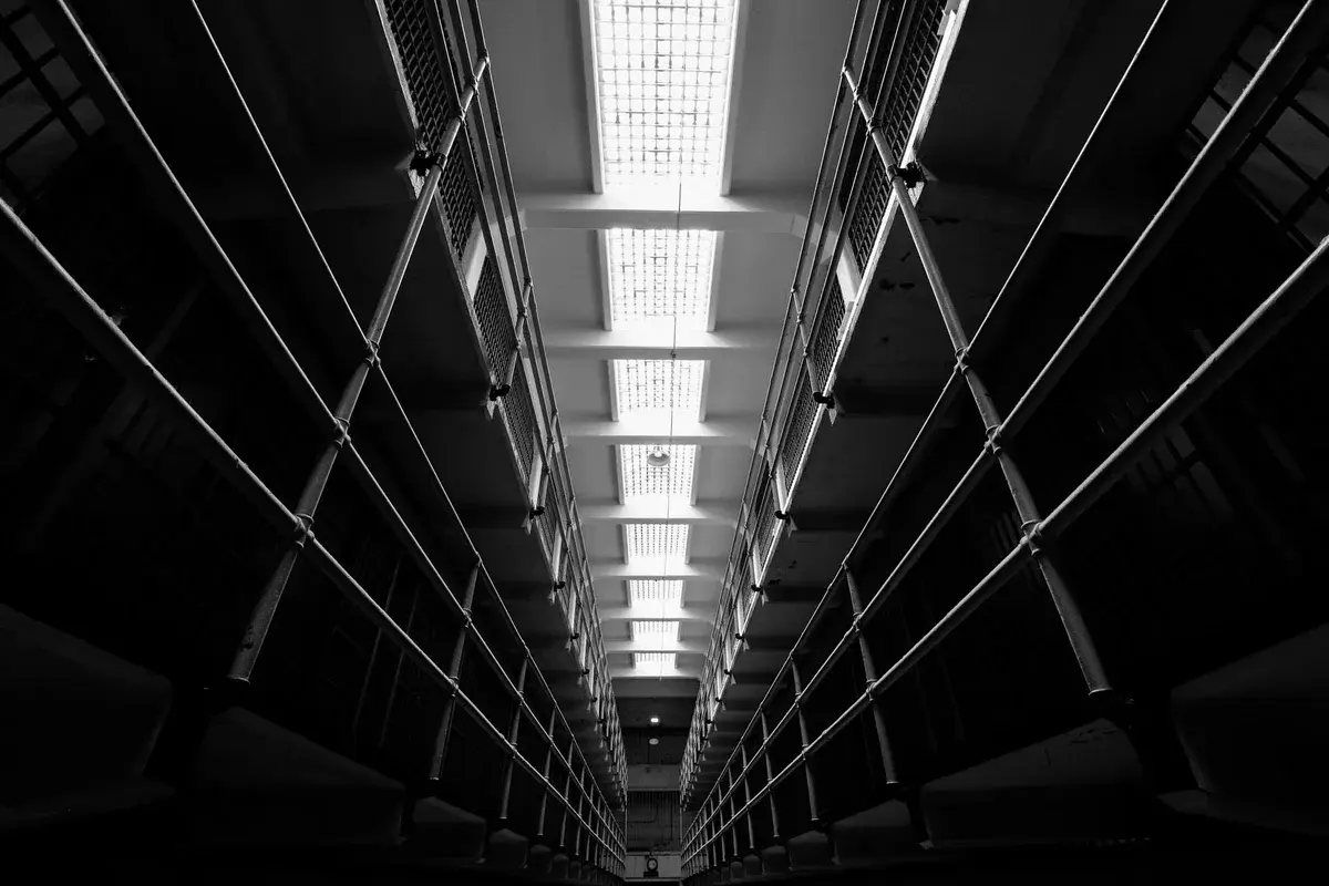 Black-and-white interior of Alcatraz Prison with a long corridor and cell blocks.