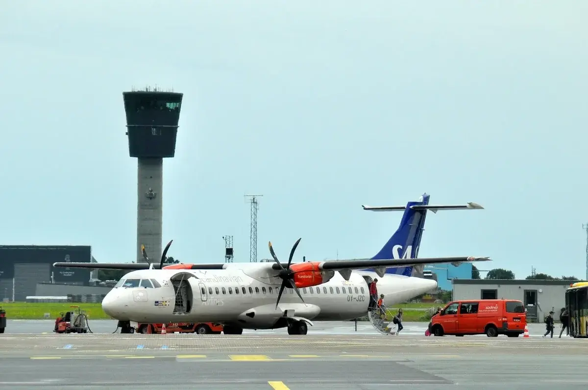 Propeller airplane on airport tarmac with control tower