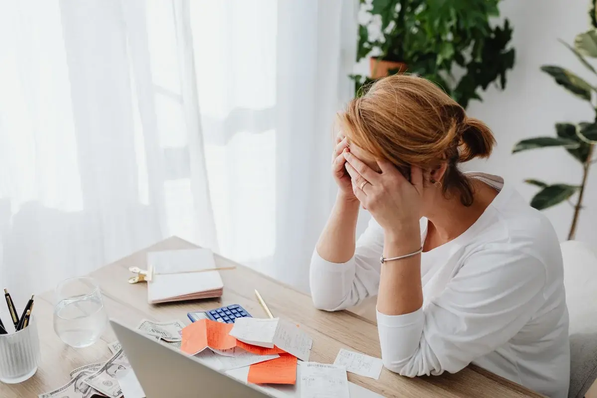 Woman stressed at desk with financial receipts
