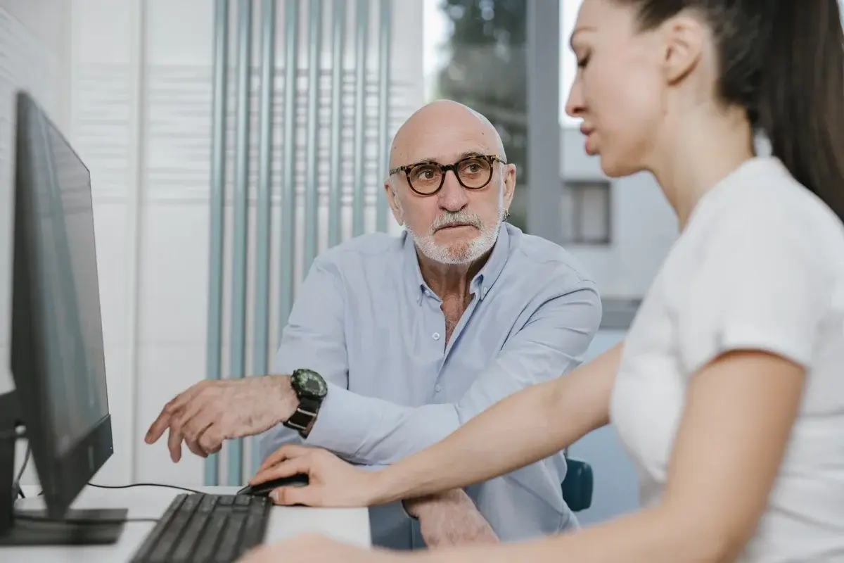 Elderly man consulting with female doctor at computer