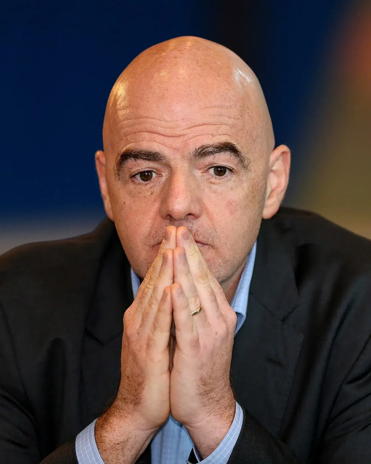 Thoughtful bald man in suit resting face on hands