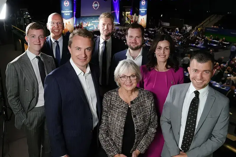 Group of eight people in formal attire at a political event