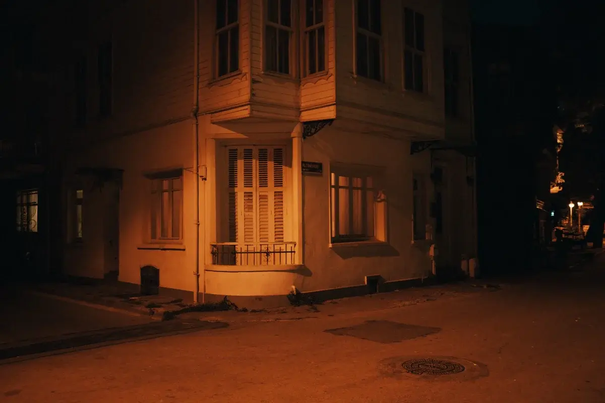 A warmly lit apartment building corner at night on a quiet street.