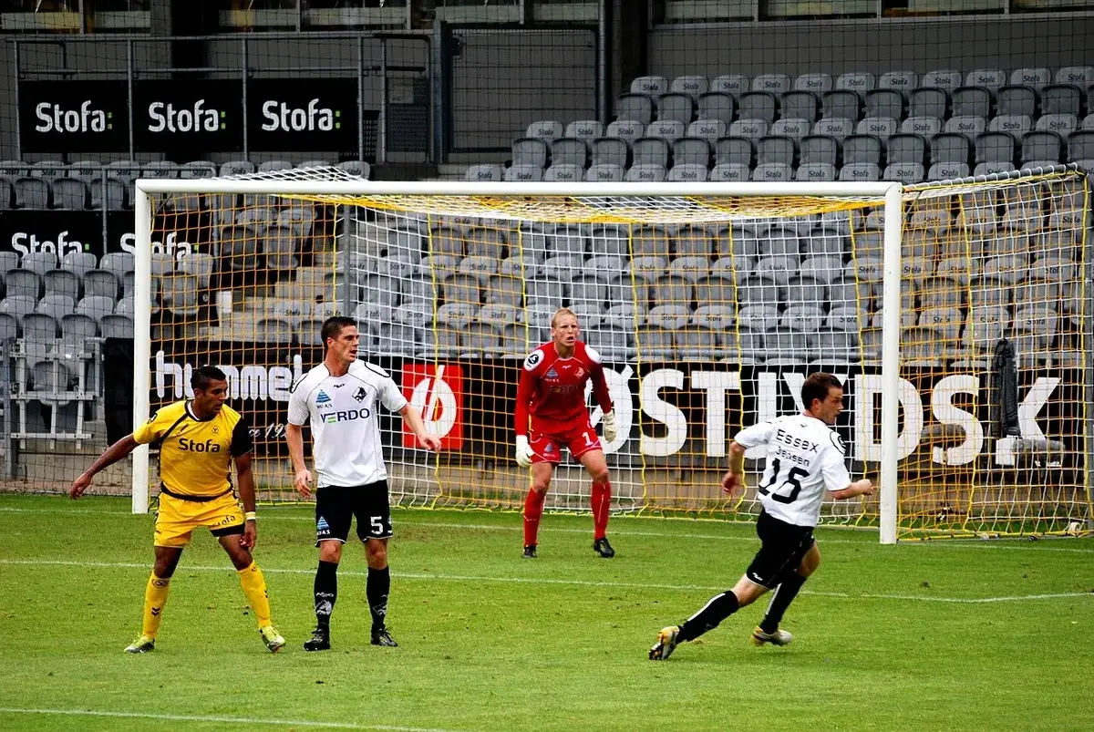 Football players and goalkeeper near goalpost during match