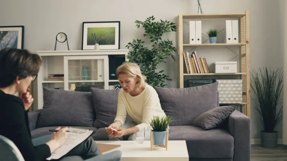 A woman speaking with a therapist in a cozy living room.
