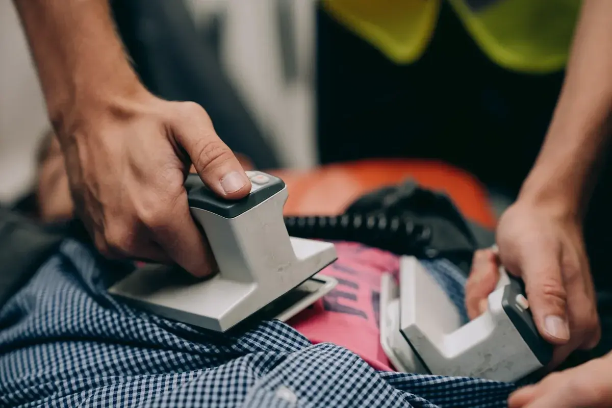 hands using defibrillator on patient