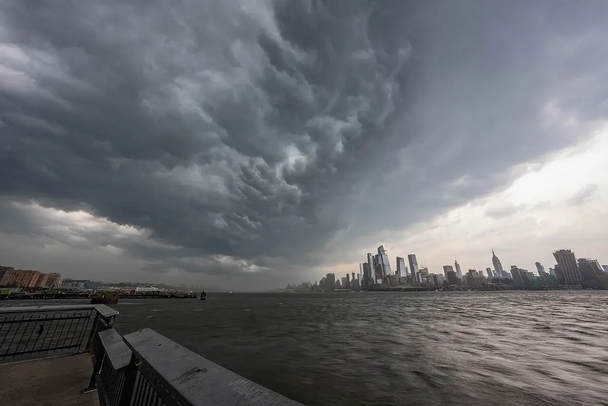 Dark storm clouds over the New York City skyline and water.