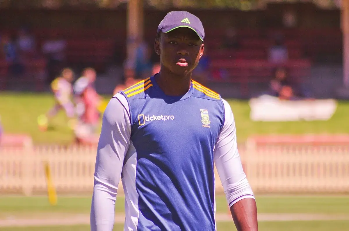 Kagiso Rabada standing on a cricket field during a match.