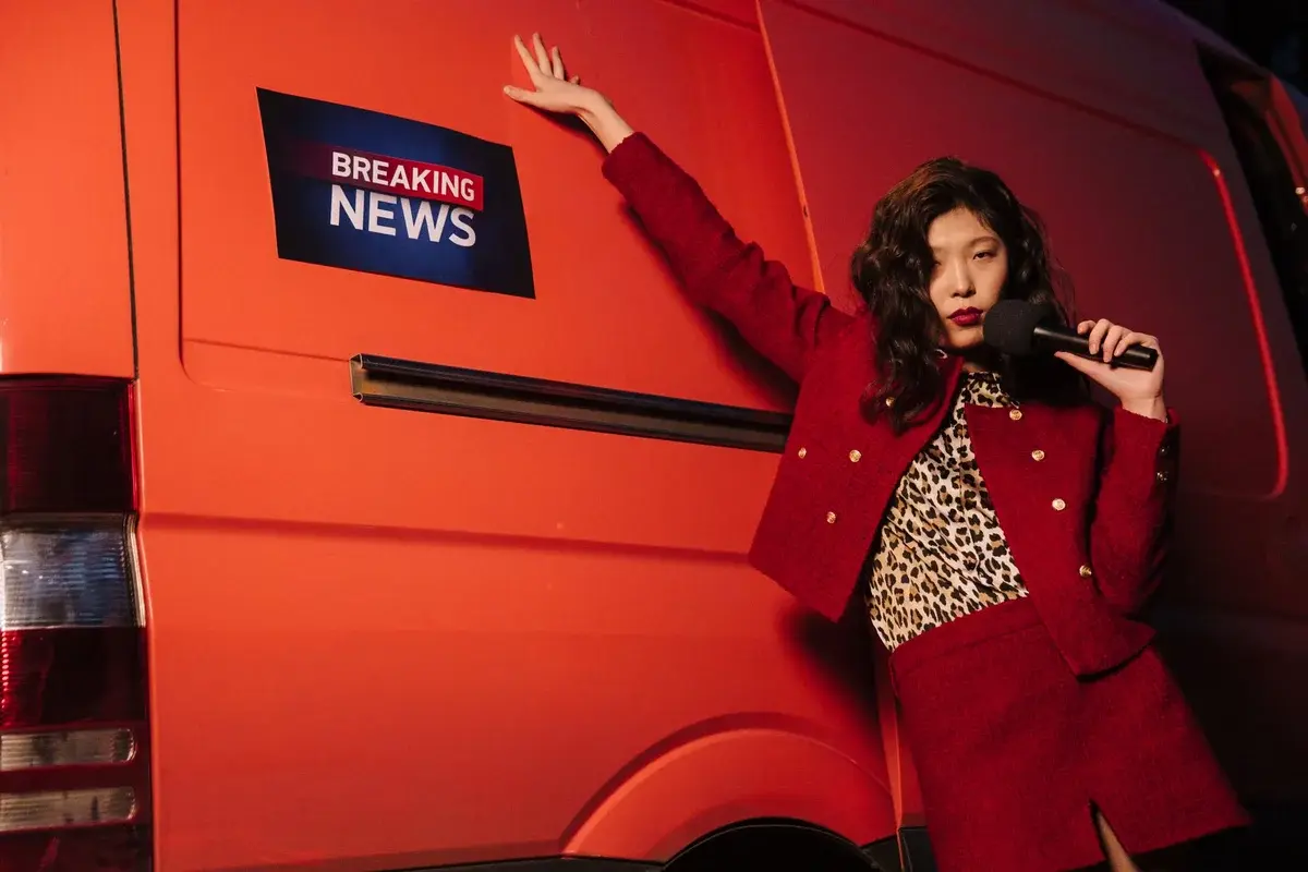 Female reporter posing next to news van with microphone