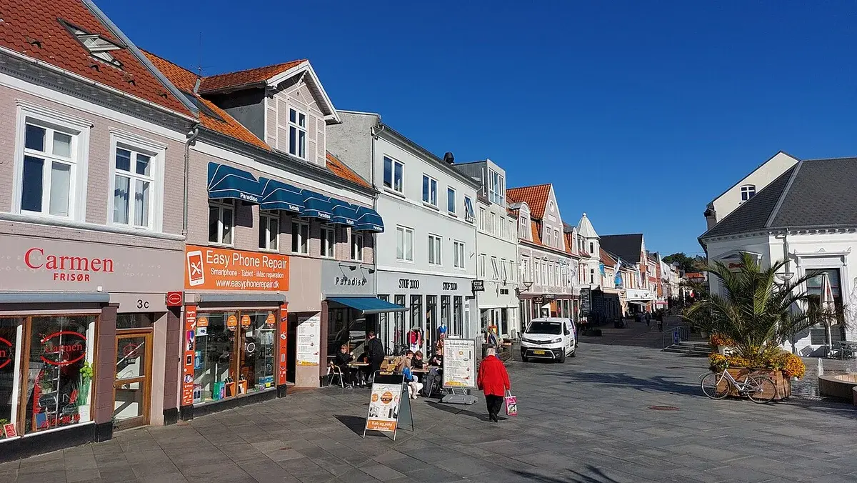Street view of Vestergade in Vejle with shops and pedestrians on a sunny day.