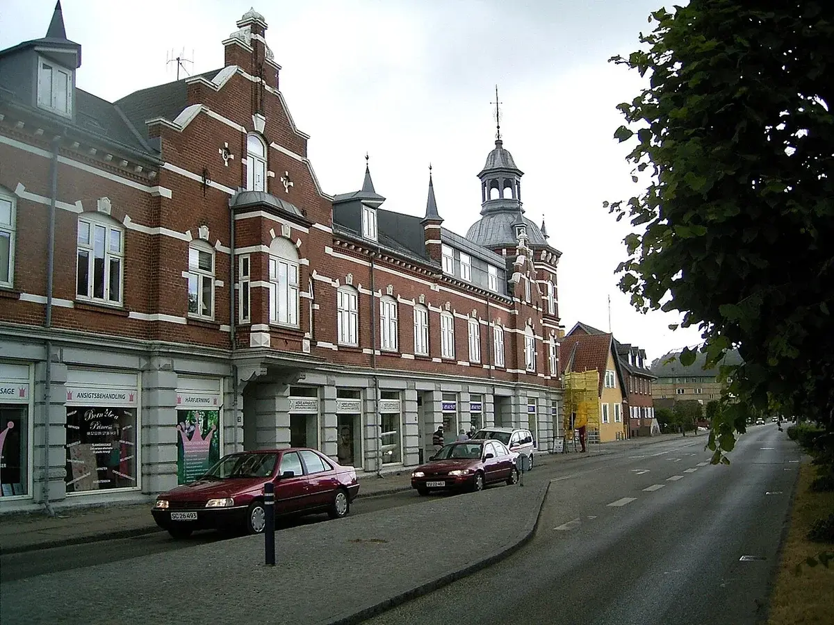 Historic brick buildings and parked cars on Jernbanegade street in Hobro