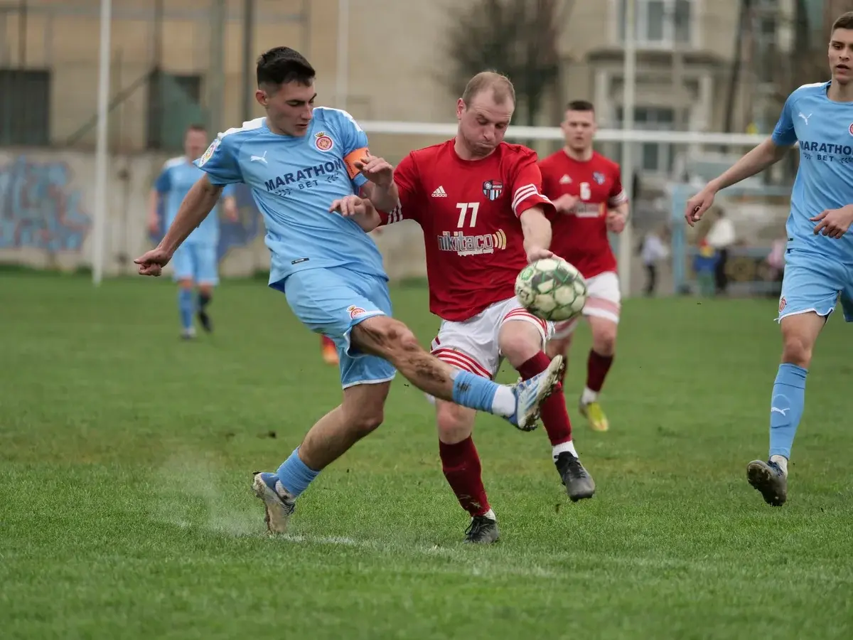 Two soccer players from opposing teams competing for the ball