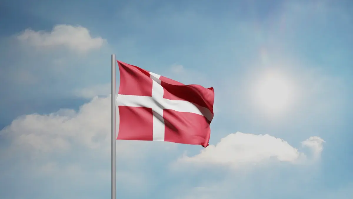 The Danish flag waving against a sunny blue sky.
