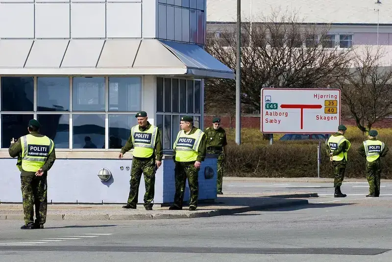 Danish police and Home Guard in uniform at a street corner with directional road signs