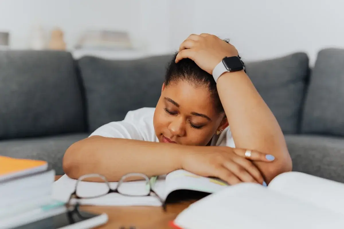 Woman resting head on open books at table