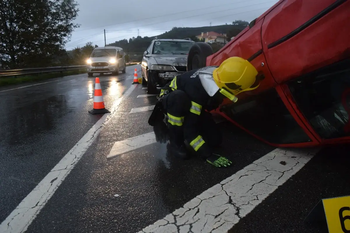 Firefighter aiding at overturned car accident on rainy road