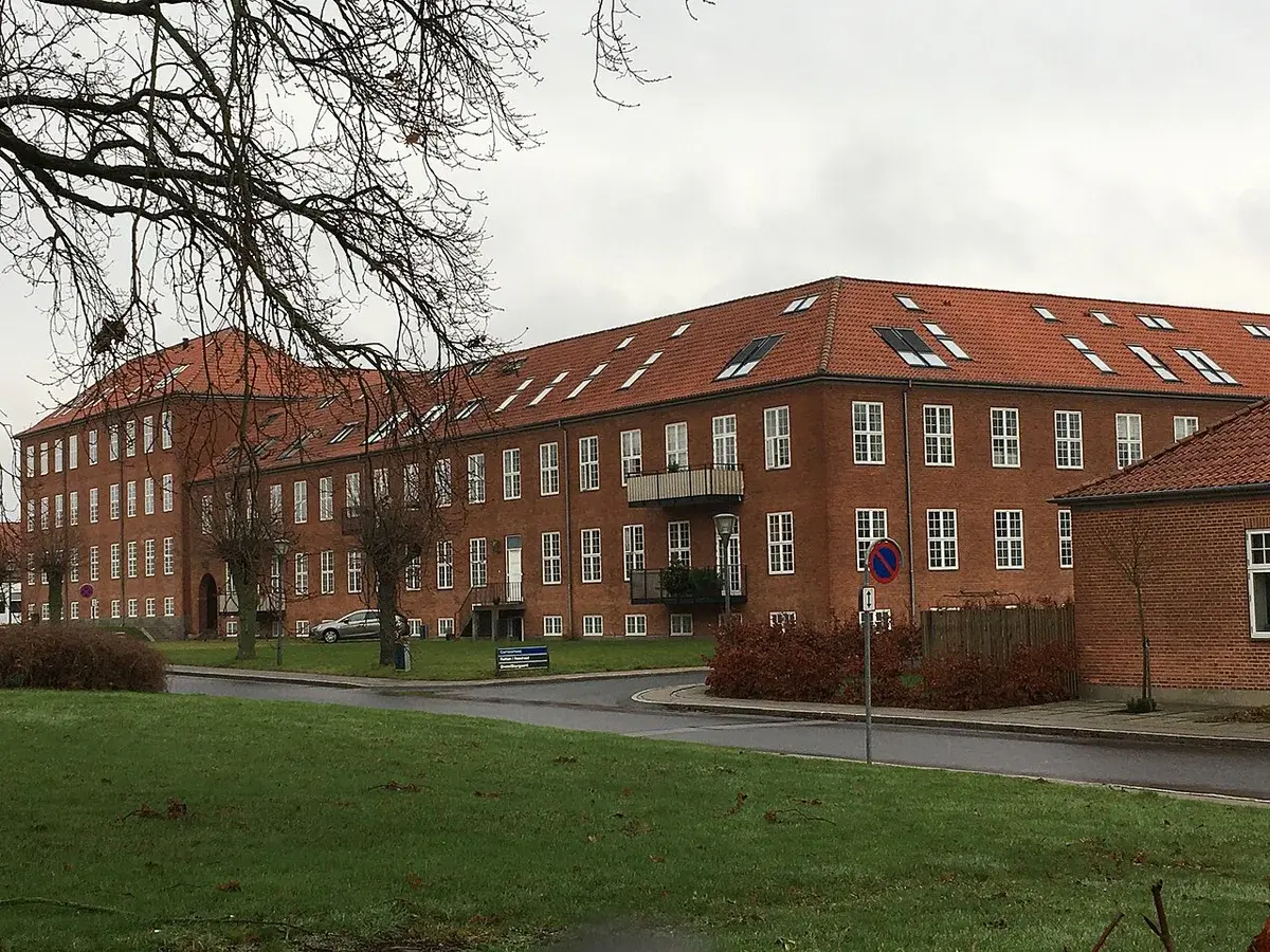 Brick building complex with red tiled roof and many windows