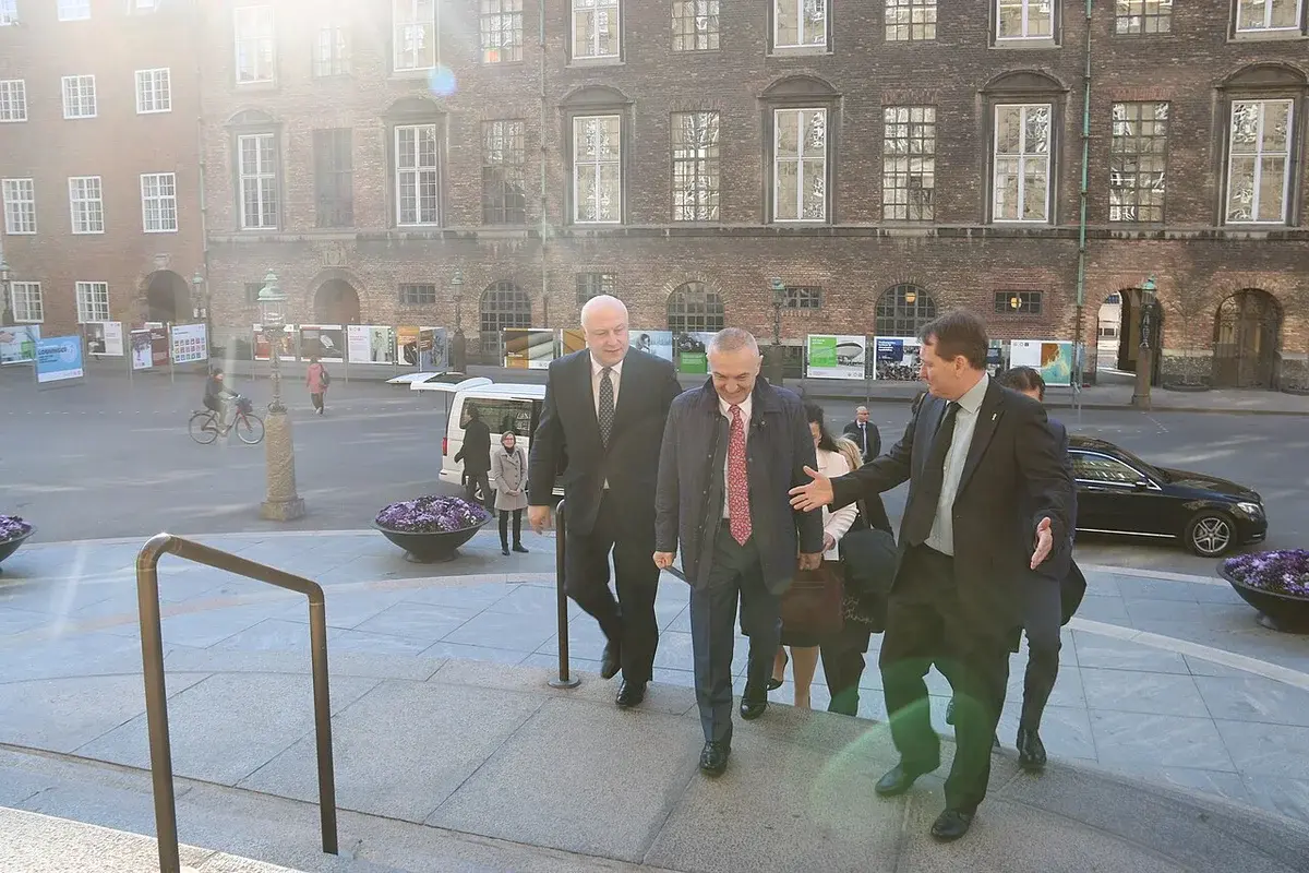 Officials walking up the steps outside the Danish Parliament, with one man welcoming another.