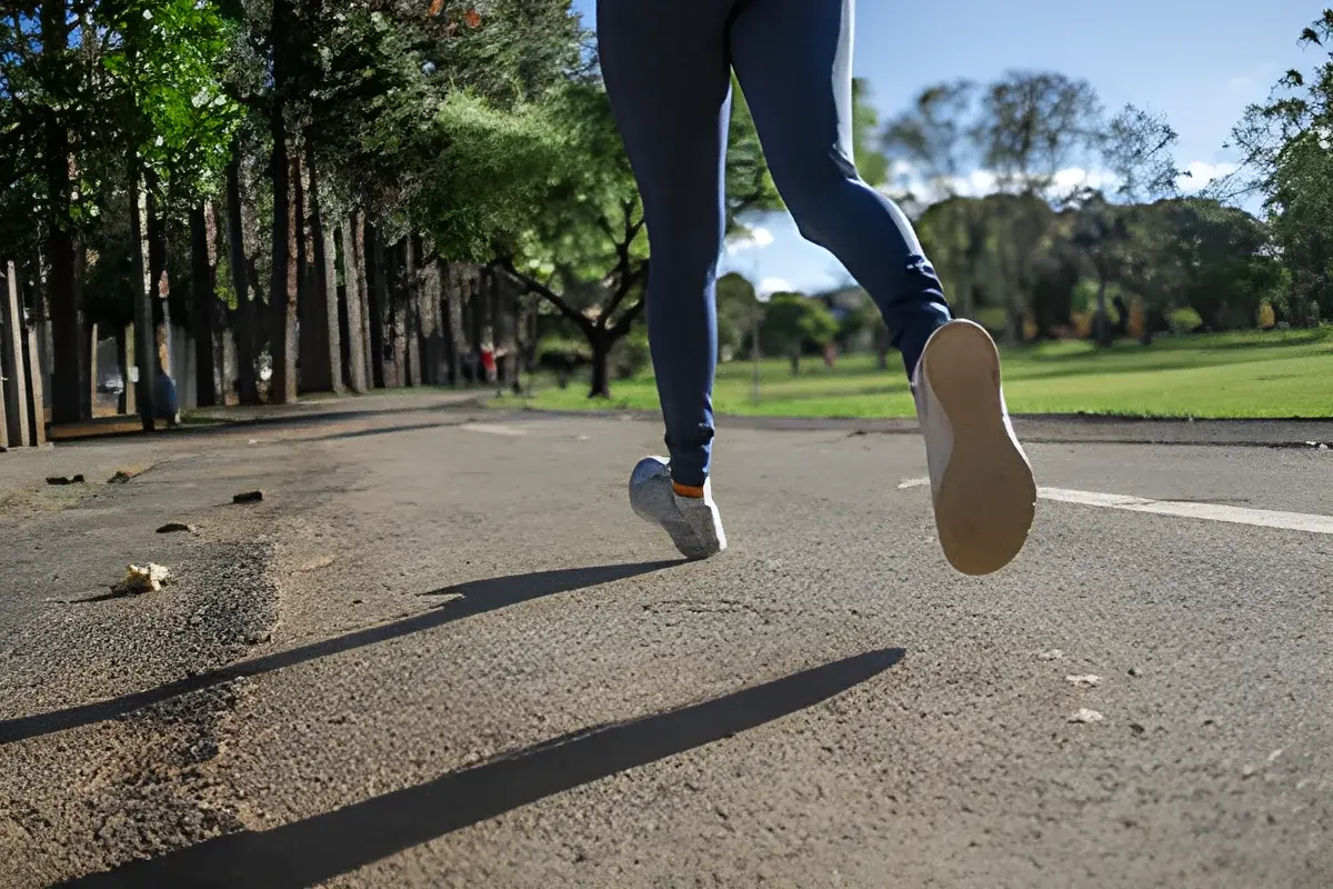 Close-up of a person running on a park path showing legs and shoes
