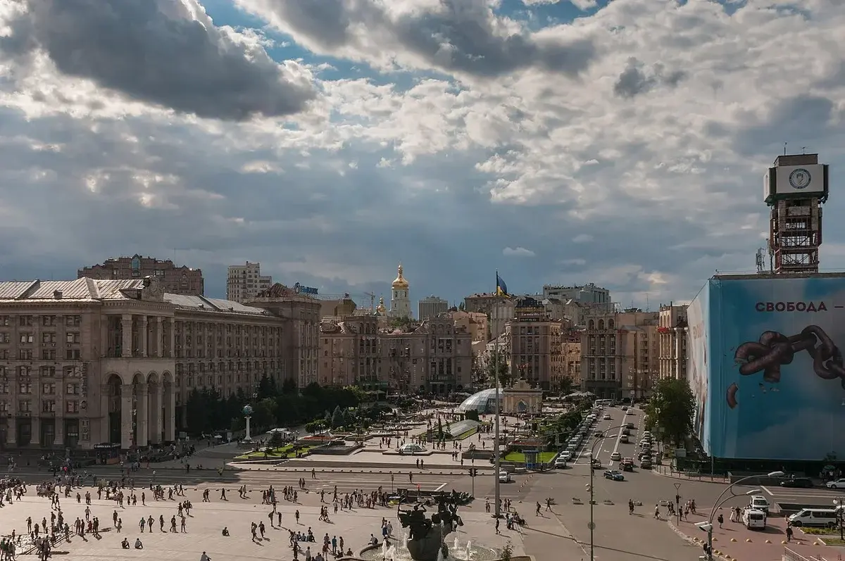 Wide view of Maidan Nezalezhnosti in Kyiv with people in the square and city buildings around it.