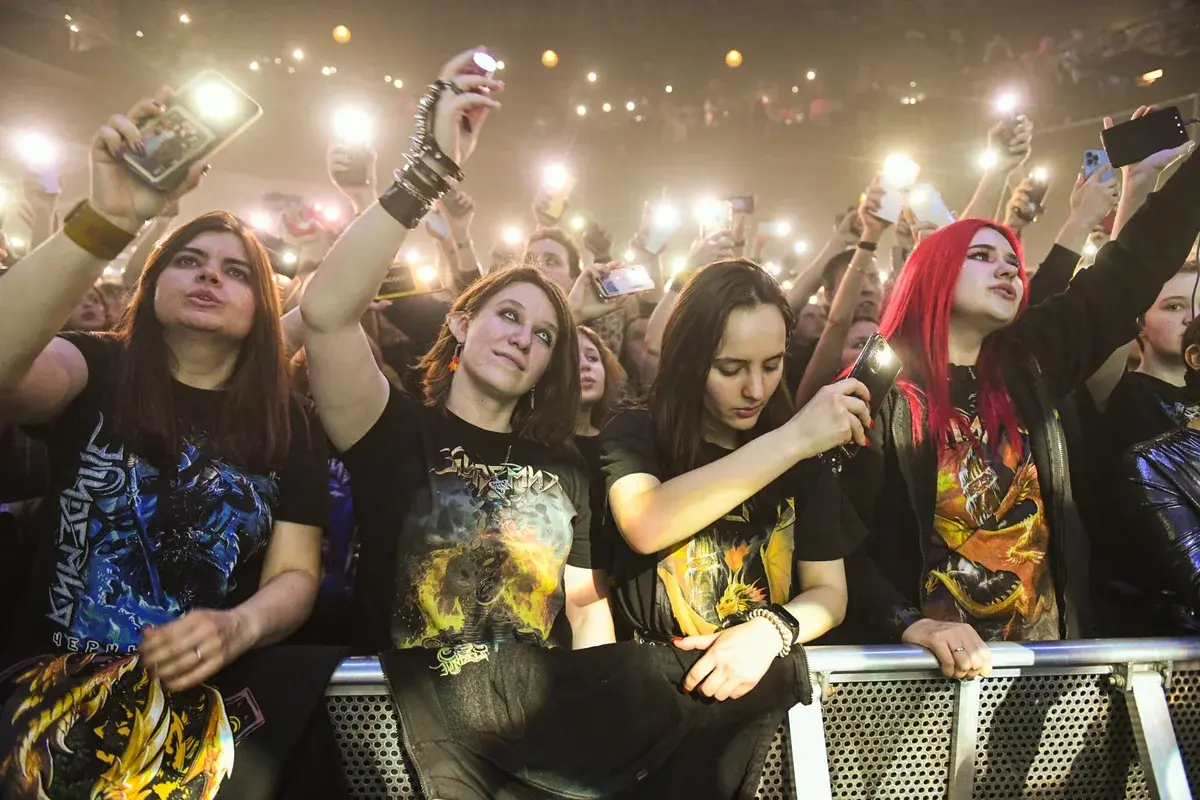 Crowd of fans at a live rock concert holding up phones.